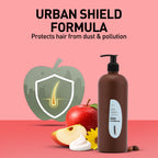 Brown bottle of apple conditioner with an apple and apple slices on a pink background, featuring 'Urban Shield Formula'.
