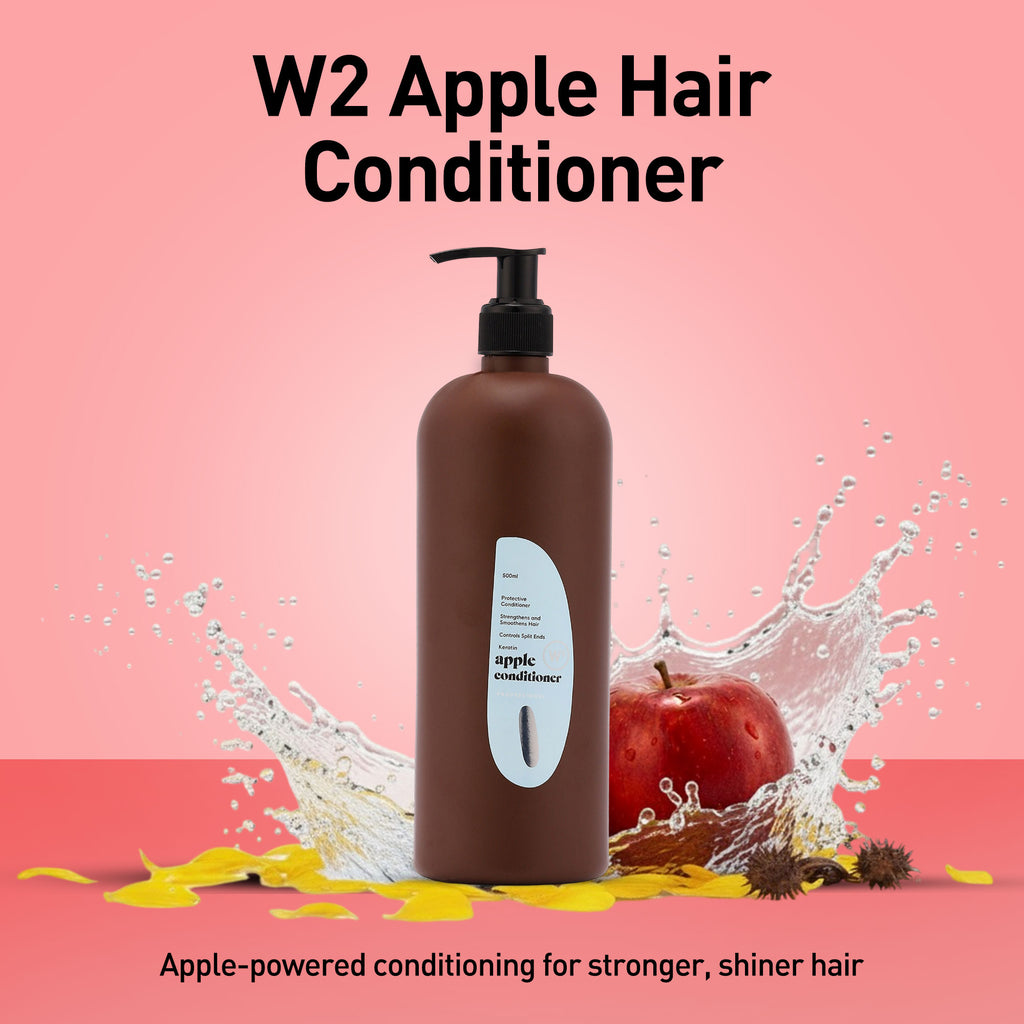 Brown hair conditioner bottle with apple and water splash on a pink background
