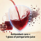 Pomegranate juice being poured into a glass with pomegranate seeds and a pitcher in the background.